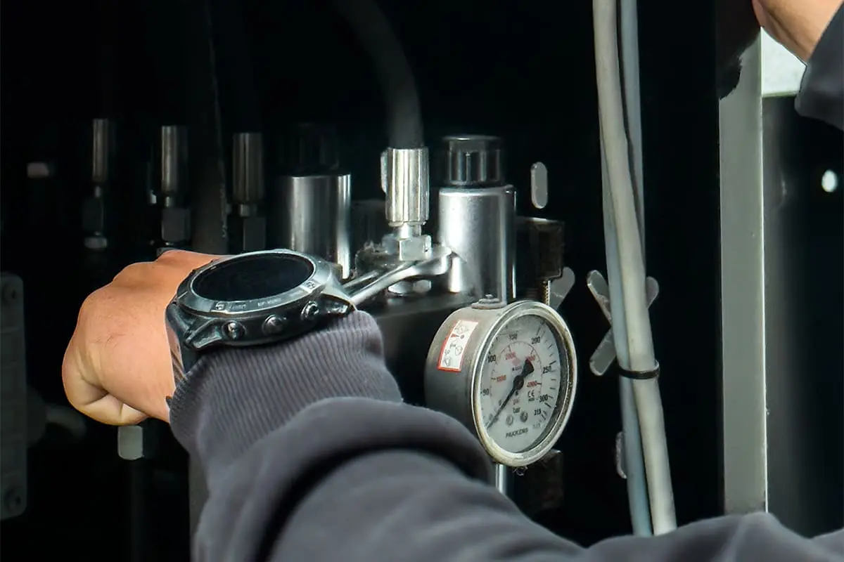 Technicien contrôlant la pression d’un système hydraulique sur une machine industrielle